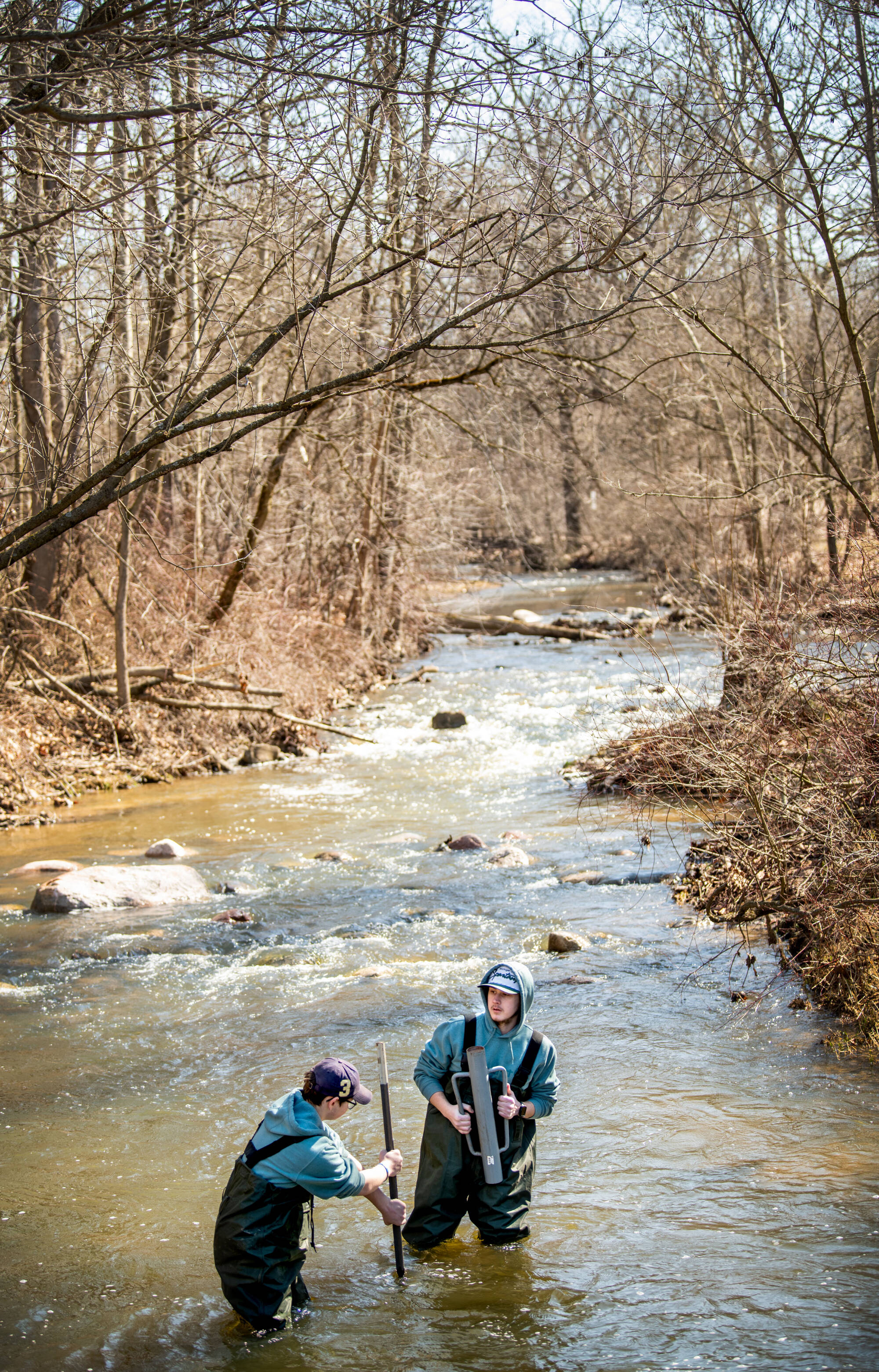 Two students placing a pole in the middle of a stream